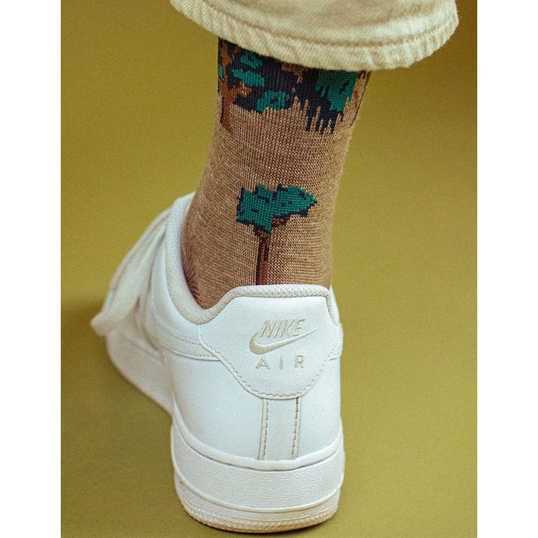 Kaki sok met bosprint bij de hiel op een witte sneaker.